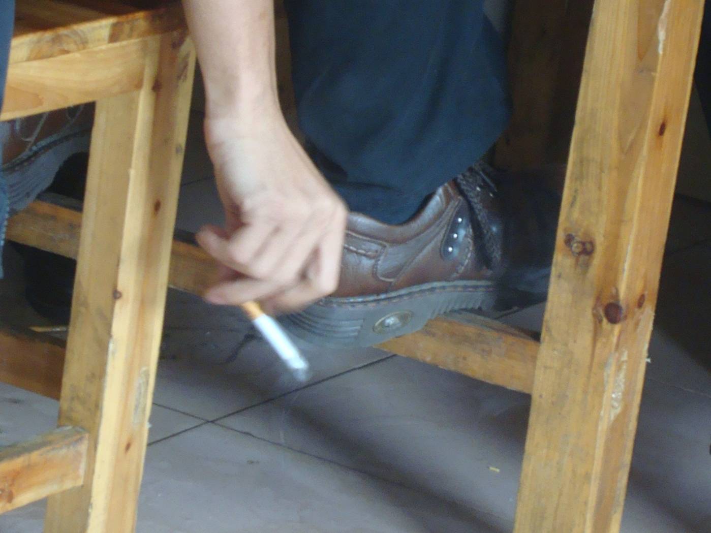 Picture: The world is their ashtray.  A smoker flicks his ash onto the restaurant floor.  We've seen them butt cigarettes out on carpets.  Often they just drop them to smolder and stink, not bothering to butt them out at all.  Haikou, Hainan Island, China