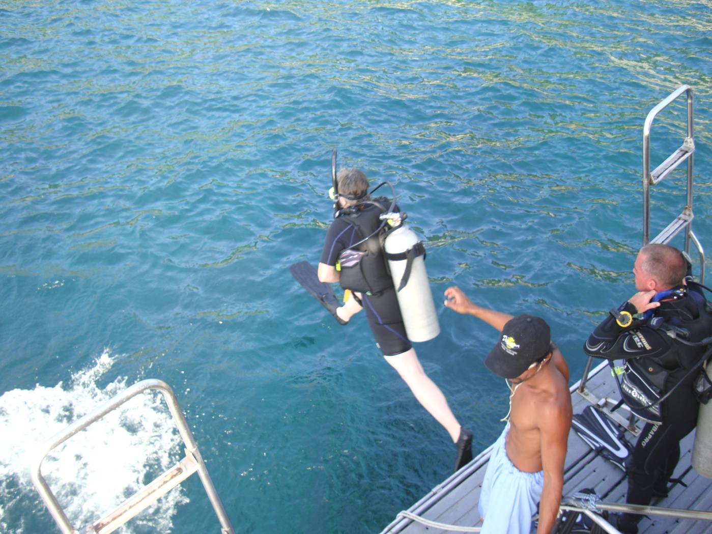 Picture:  Ruth takes the big step into the water for her third dive of the day with Dive Asia.  Left hand on the weight belt.  Right hand on the mask.  Phuket, Thailand