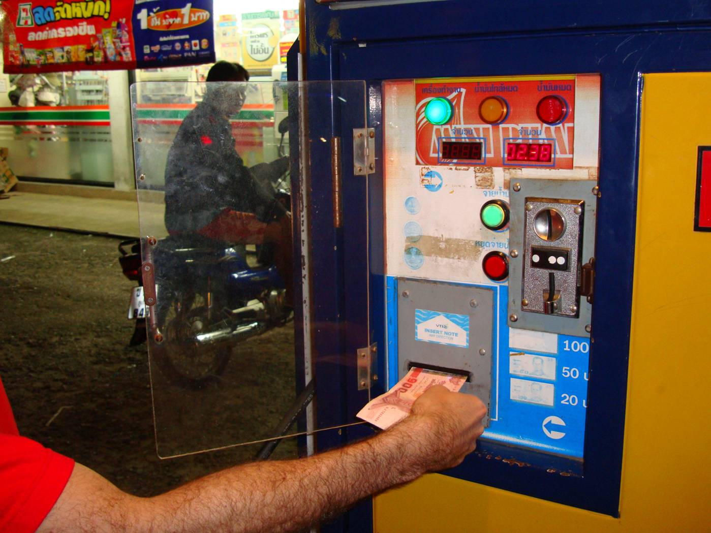 Picture:  Feeding money into the gas machine, Phuket Island, Thailand