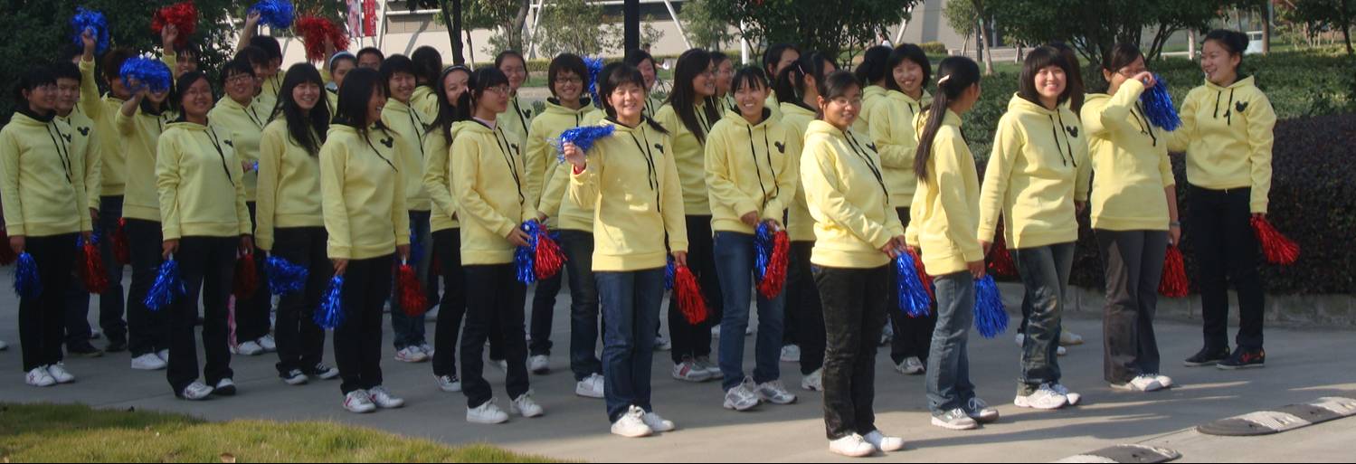 Picture:  I can only assume they are performing at the sports day.  Girls in identical yellow jackets with pom poms.  Jiangnan University, Wuxi, China