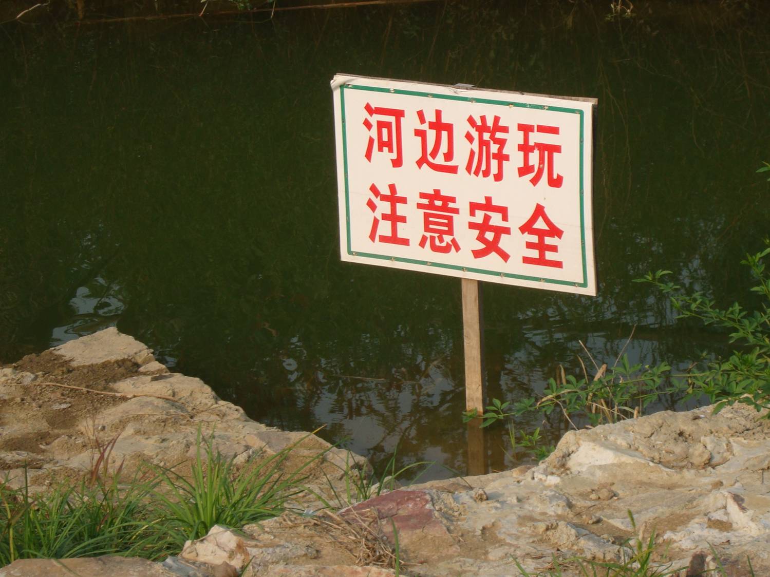 picture: Sign warning of deep water, advising careful play.  Canal side park near Jiangnan University, Wuxi, China