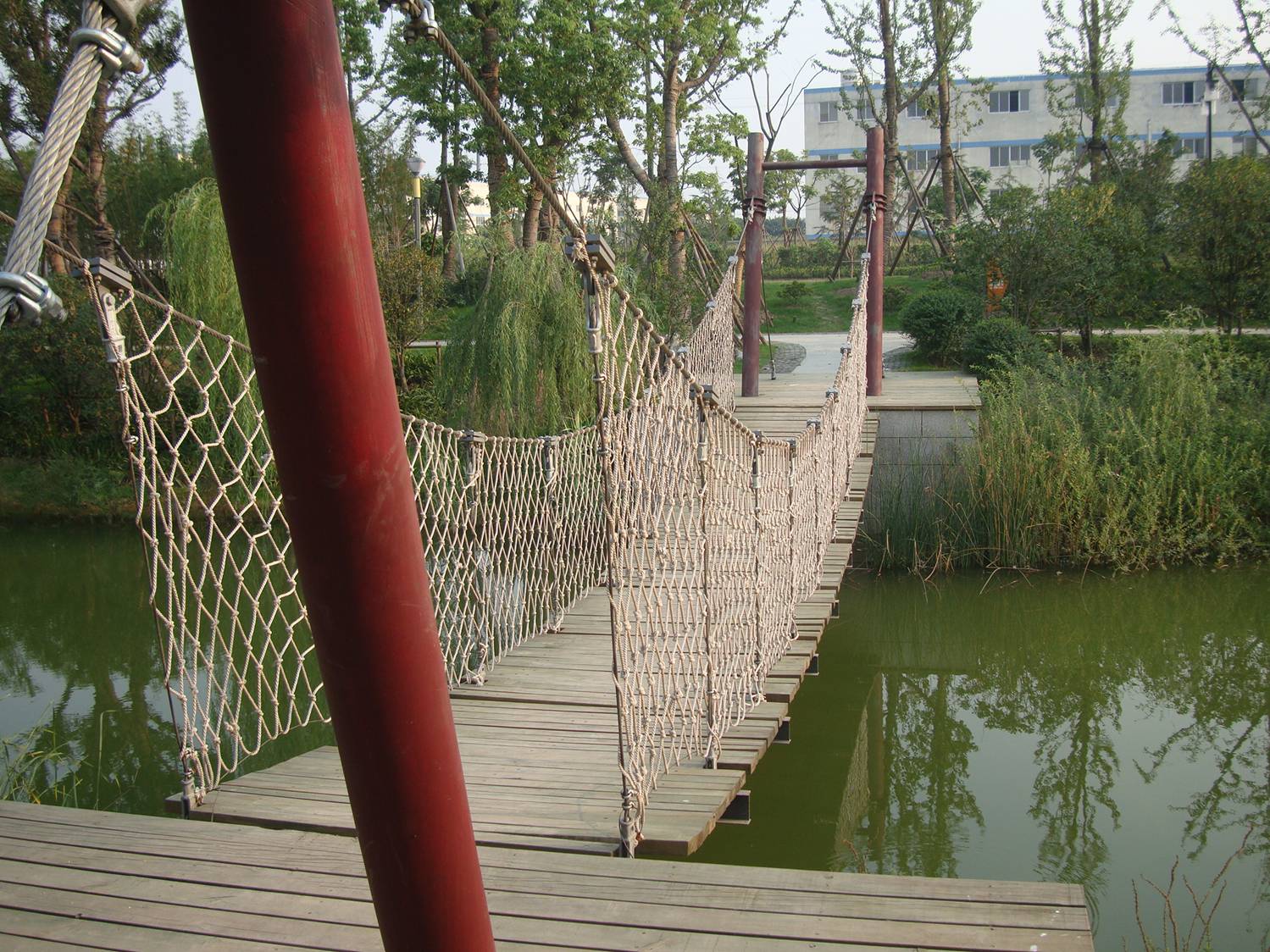 picture: A rope bridge over untroubled waters.  Canal side park near Jiangnan University, Wuxi, China