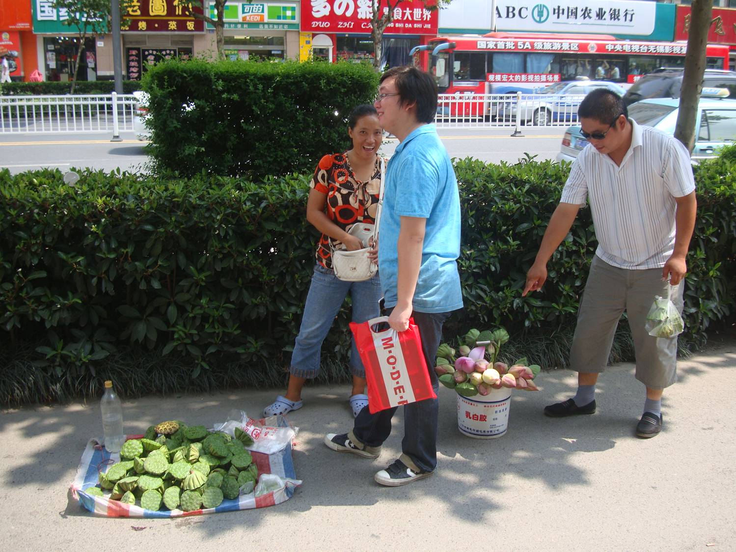 picture:  The street seller is trying to escape from the camera.  Lotus roots for sale on the streets of Wuxi, China