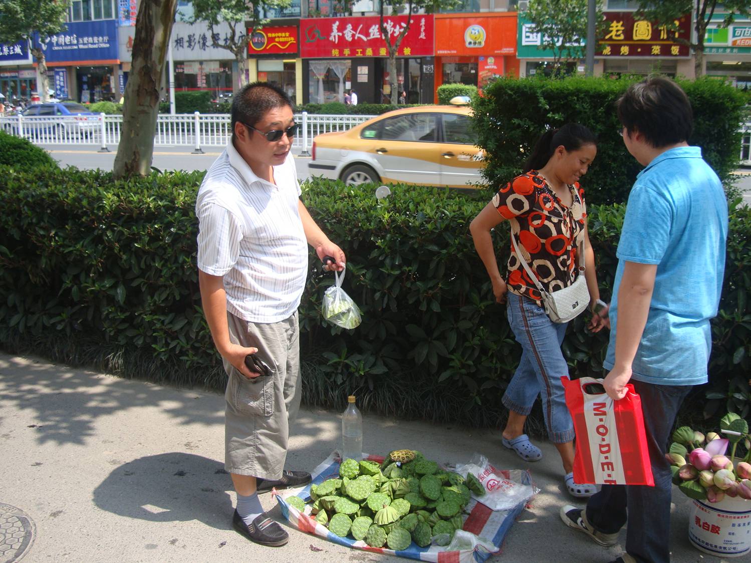 picture:  The street seller is trying to escape from the camera.  Lotus roots for sale on the streets of Wuxi, China
